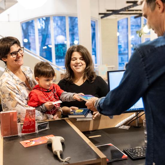 Familie afleverer bøger til bibliotekar. Foto: Nikolai Linares. Centralbibliotekernes Fotobank.