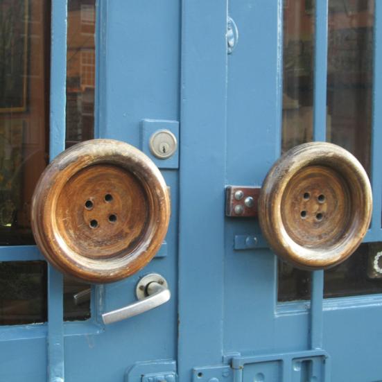 Dør med to store knapper som håndtag og et "open"-skilt