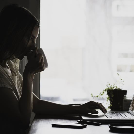 ung kvinde drikker kaffe, studerer på en bærbar computer